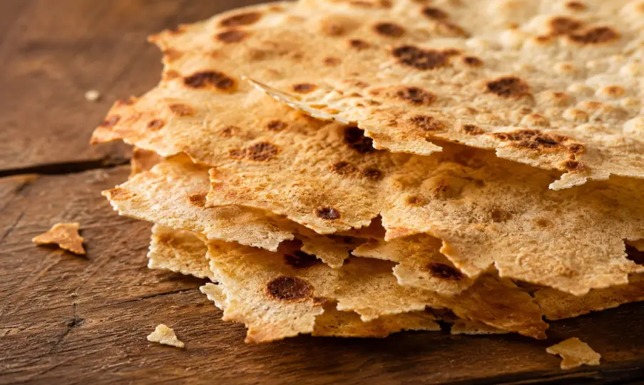 Nahaufnahme von dünnem knusprigem Pane Carasau mit gebrochener Struktur und goldbrauner Oberfläche