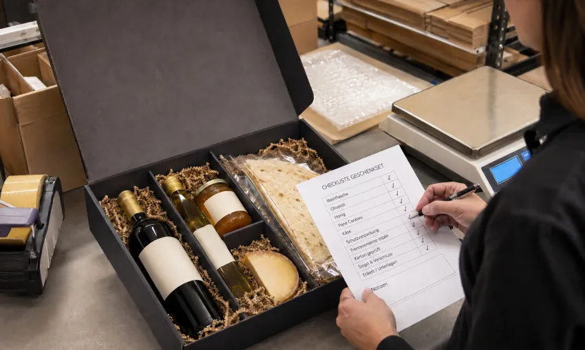 Mitarbeiter prüft Bruchsicherung und Verpackung eines sardischen Geschenksets vor dem Versand