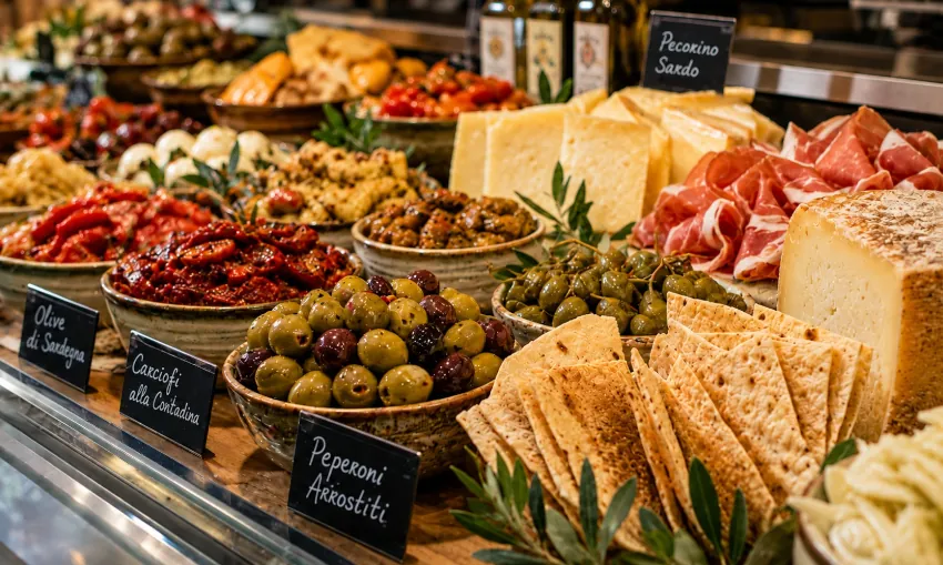 Präsentation sardischer Antipasti mit Oliven, Käse, Paprika und eingelegtem Gemüse in einer Feinkosttheke